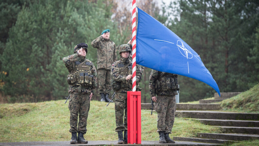 Four US soldiers salute the NATO flag as it’s raised