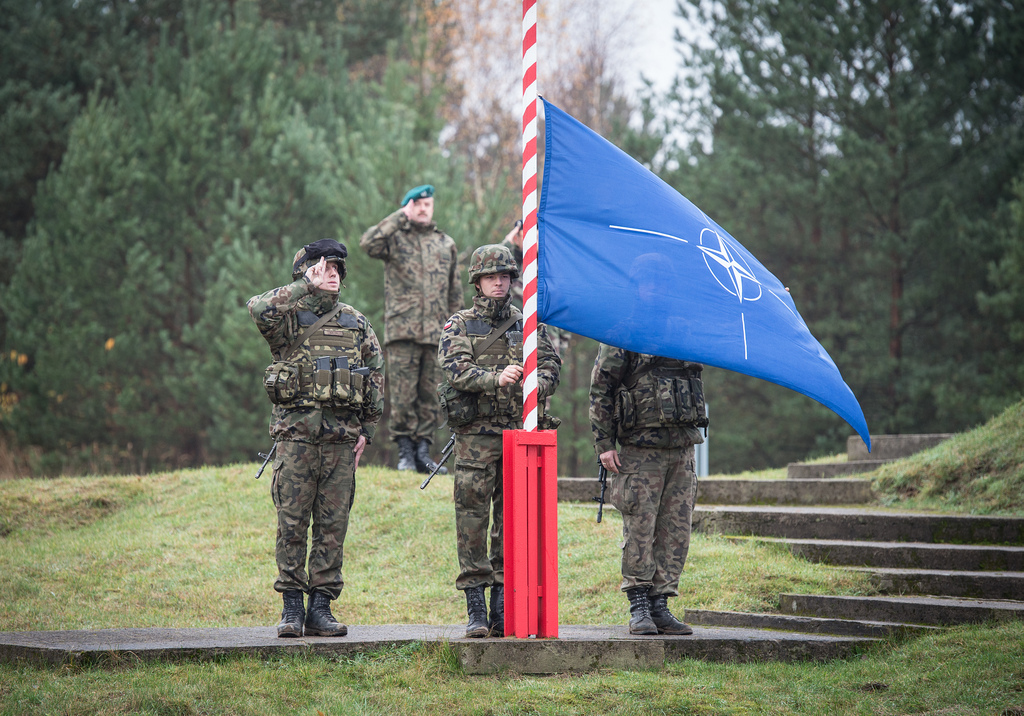 Four US soldiers salute the NATO flag as it's raised
