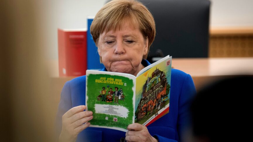 Chancellor Angela Merkel reads a brochure on the German constitution