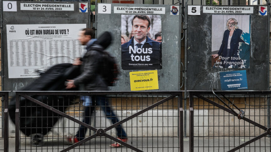 epa09907999 A man walks next to billboards with posters for French President Emmanuel Macron (C) and previous presidential candidate Marine Le Pen (R), in Paris, France, 25 April 2022. Emmanuel Macron defeated Marine Le Pen in the final round of France’s presidential election on 24 April, with exit polls indicating that Macron led with approximately 58 percent of the vote. Photo: picture alliance/EPA/Mohammed Badra