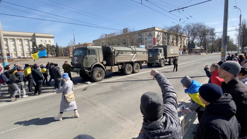 A demonstrator gestures as others, displaying Ukrainian flags, chant “go home” and walk towards Russian military vehicles at a pro-Ukraine rally amid Russia’s invasion, in Kherson, Ukraine March 20, 2022 in this still image from video obtained by REUTERS ATTENTION EDITORS – THIS IMAGE HAS BEEN SUPPLIED BY A THIRD PARTY. REUTERS HAS VERIFIED THE LOCATION