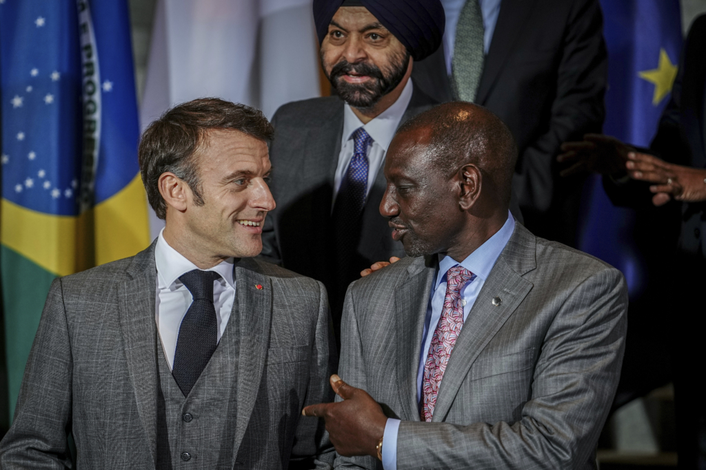 French President Emmanuel Macron, left, and the President of Kenya, William Ruto, stand together for a family photo in front of Ajay Banga, President of the World Bank, at the "Compact with Africa" - G20 Investment Summit 2023 conference, in Berlin, Monday Nov. 20, 2023.