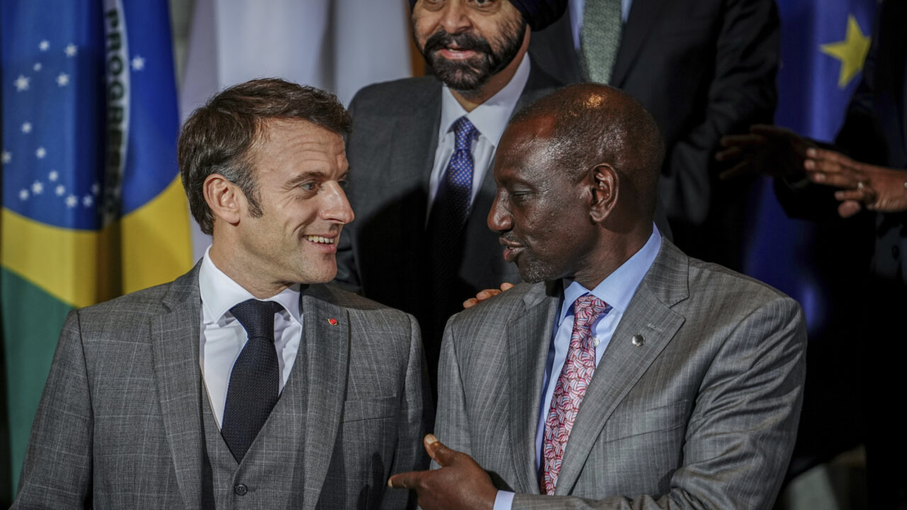 French President Emmanuel Macron, left, and the President of Kenya, William Ruto, stand together for a family photo in front of Ajay Banga, President of the World Bank, at the “Compact with Africa” – G20 Investment Summit 2023 conference, in Berlin, Monday Nov. 20, 2023