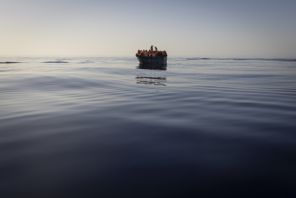 Migrants with life jackets provided by volunteers of the Ocean Viking, a migrant search and rescue ship run by NGOs SOS Mediterranee and the International Federation of Red Cross (IFCR), still sail in a wooden boat as they are being rescued, Aug. 27, 2022, in the Mediterranean sea. The back-to-back shipwrecks of migrant boats off Greece that left at least 22 people dead this week has once again put the spotlight on the dangers of the Mediterranean migration route to Europe.
