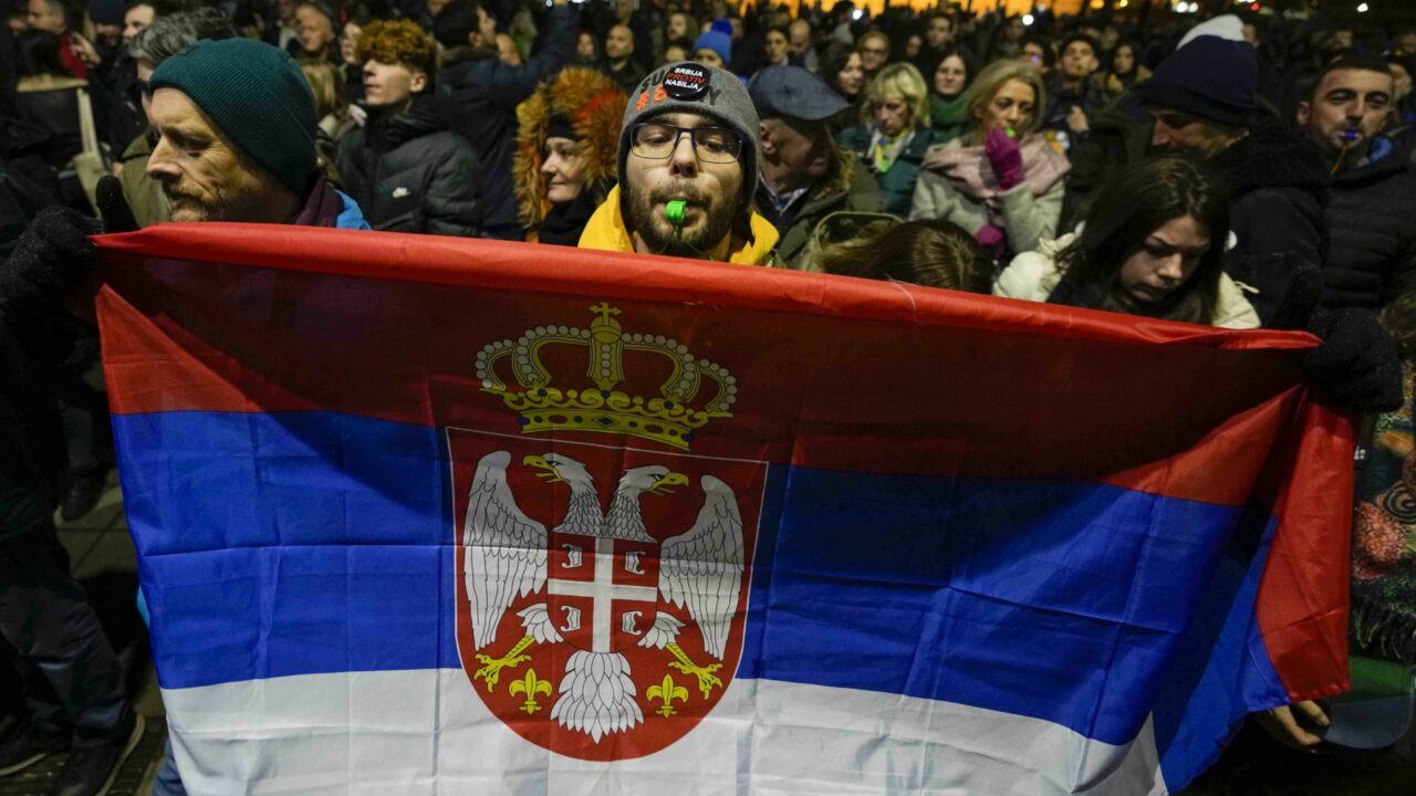 A man blows a whistle and holds a Serbian flag outside the electoral commission building during opposition protest in Belgrade, Serbia, Tuesday, Dec. 19, 2023. Several thousand people rallied to protest alleged fraud at the ballot for municipal authorities in Belgrade. Serbia’s ruling populists insisted on Tuesday that weekend snap elections were free and fair despite criticism from international observers who noted multiple irregularities during the vote in the Balkan nation that is a candidate for European Union membership. (AP Photo/Darko Vojinovic)