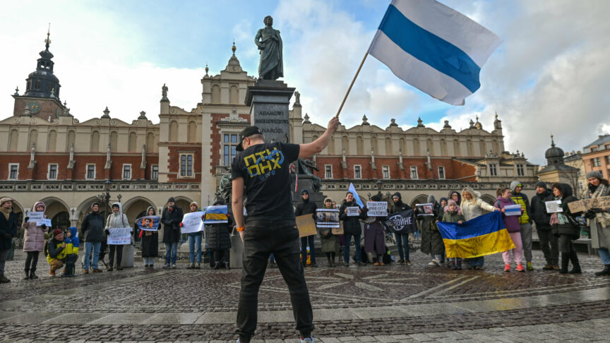 KRAKOW, POLAND – FEBRUARY 25, 2023: An activist holds the white-blue-white flag, a symbol of opposition to the 2022 Russian invasion of Ukraine, during a peaceful gathering of members from the local Russian diaspora in Krakow at the Adam Mickiewicz Monument in the heart of Krakow’s Main Square, in Krakow’s Main Square, on February 25, 2023, in Krakow, Poland. The group of thirty activists came together to voice their opposition to the war in Ukraine under Vladimir Putin’s leadership. In a silent protest, they demonstrated their support for Ukraine, their commitment to promoting peace and unity amidst the ongoing conflict. (Photo by Artur Widak/NurPhoto)