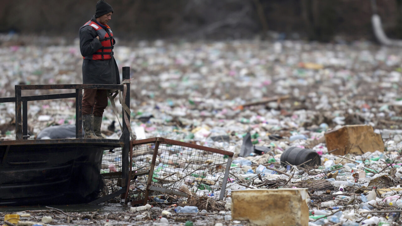Utility company workers push the waste to the shore of Lim river near Priboj, Serbia, Monday, Jan. 30, 2023. Plastic bottles, wooden planks, rusty barrels and other garbage dumped in poorly regulated riverside landfills or directly into the rivers accumulated during high water season, behind a trash barrier in the Lim river in southwestern Serbia. (AP Photo/Armin Durgut)