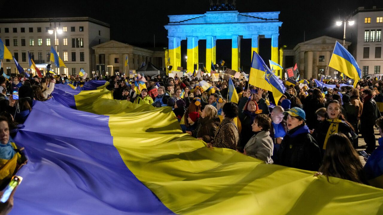 Protesters Arrive at the Brandenburg Gate, illuminated in Ukrainian colors, during a demonstration against Russia’s war on Ukraine as they mark the third anniversary of the full-scale invasion in Berlin, Monday, Feb. 24, 2025. (AP Photo/Ebrahim Noroozi)