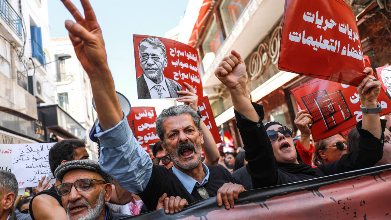 Demonstrators hold up placards depicting the image of former judge Ahmed Souab, with text in Arabic reading ”free Ahmed Souab, free Tunisia,” as they make the victory sign during a demonstration on Labour Day in Tunis, Tunisia, on May 1, 2025, to call for the release of Ahmed Souab. People also protest against the regression of freedoms and human rights in the country, calling for the fall of the regime. (Photo by Chedly Ben Ibrahim/NurPhoto)