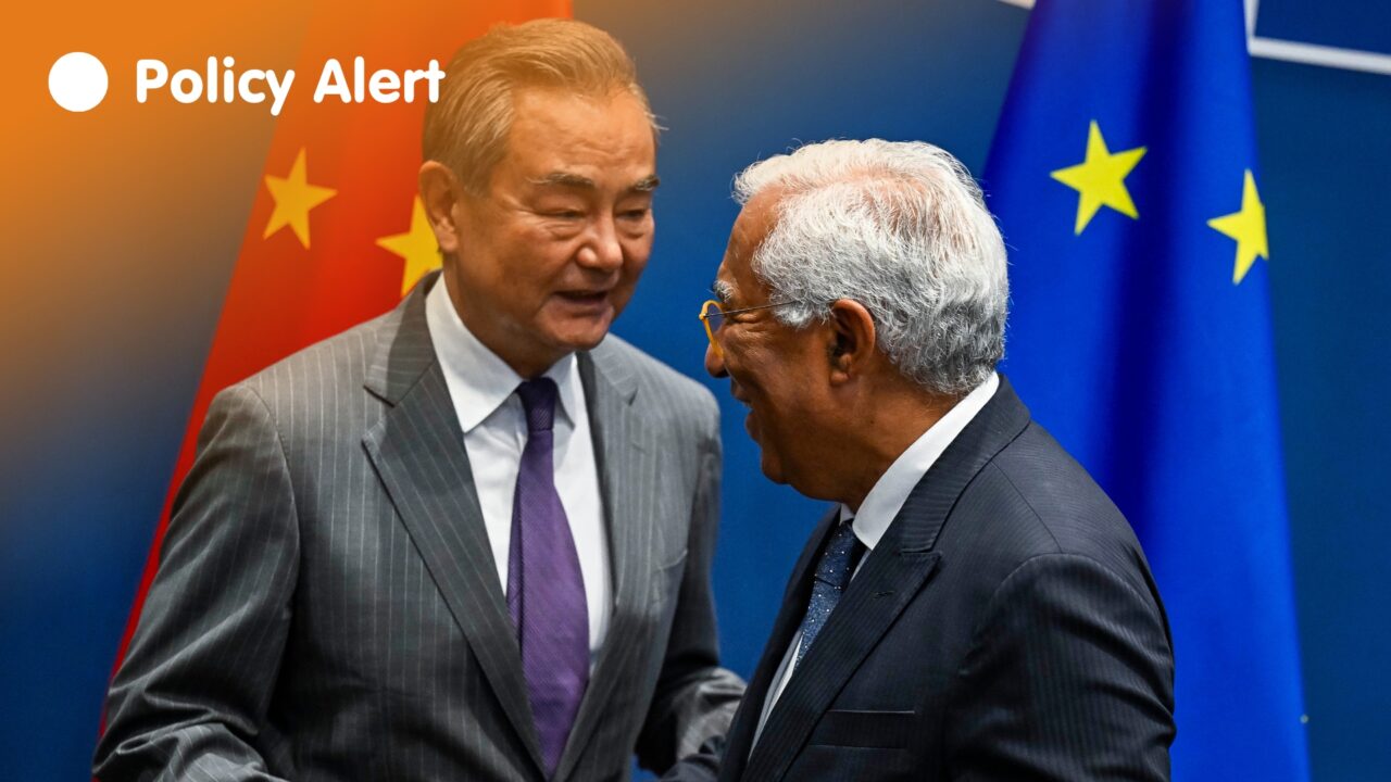 Costa Wang Yi (left, facing the camera) wearing a grey suit shakes hands with European Council President António Costa (right, facing away from the camera) against a blue backdrop with the Chinese and EU Flags