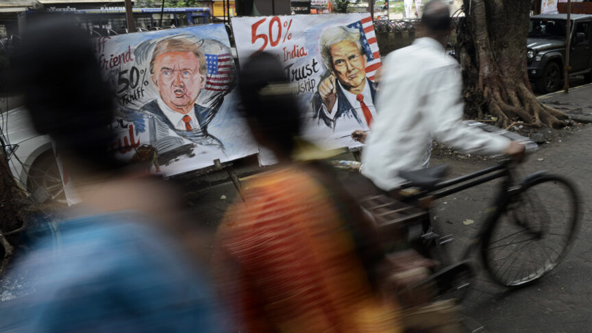 People walk past poster paintings of U.S. President Donald Trump in Mumbai, India, on August 7, 2025. The artworks criticize a proposed 50% tariff on Indian imports by the United States, reflecting local discontent over the growing trade rift between the two nations.