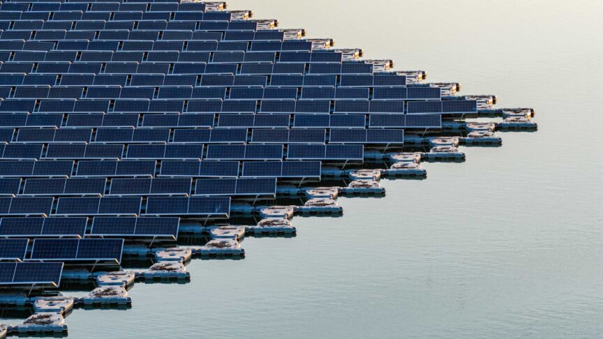 Aerial view of floating photovoltaic system with rows of solar panels on white floats over calm water during golden hour Bensheim, Hessen, Germany.
