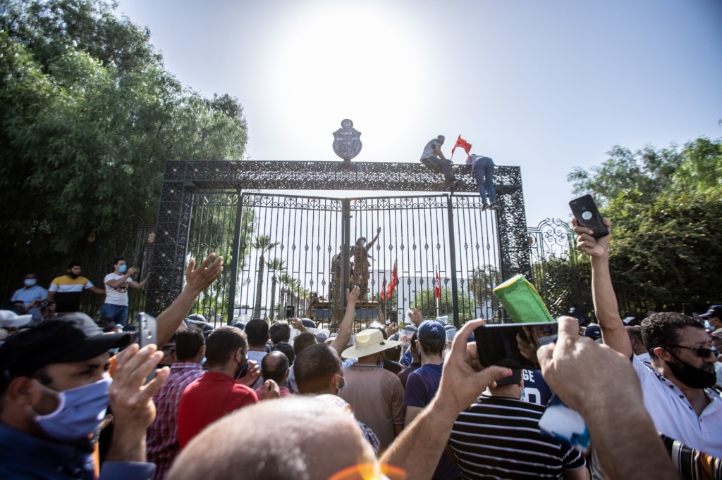 Protestors in Tunisia scale the gates of a government complex